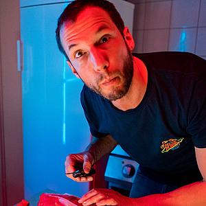 Ein Foto von Balthazar Helwig, dem Patron des Restaurants le camping, der in der Küche steht und ein Stück Fleisch zubereitet.